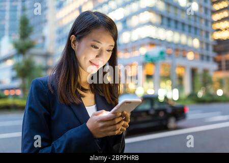 Geschäftsfrau, die nachts SMS auf dem Handy in Tokio verschickt Stockfoto