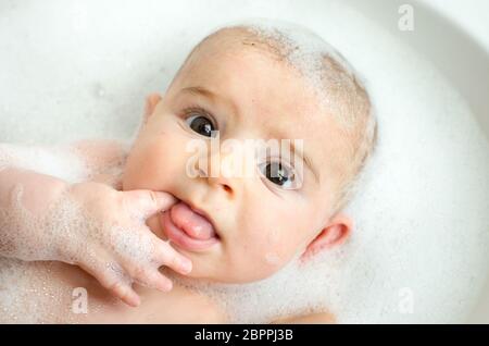 Neugeborenen Schaumbad weißer Schaum Finger Essen waschen Baby Pflege große Augen braun Stockfoto