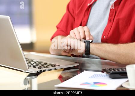 Nahaufnahme von einem Unternehmer Hände arbeiten mit einer Smartwatch mit dem Finger auf dem Touchscreen in einem Desktop im Büro Stockfoto