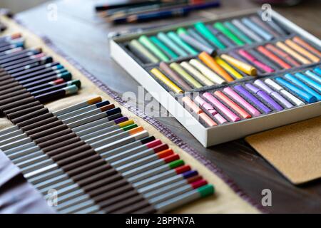 Farbstifte und Pastellkreiden auf Holztisch. Kunstmaler-Accessoires. Tageslicht. Stockfoto