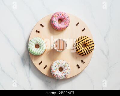 Kaffee Zeit und Donuts Zeit Konzept. Zifferblatt mit Zahlen von Dougnuts und Kaffeebohnen, Uhrzeiger als Tasse Kaffee. Holztablett als Zifferblatt, auf Stockfoto