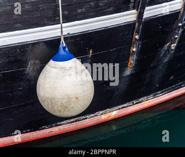 Weiße Boje, die an einem schwarzen Rumpf hängt Stockfoto