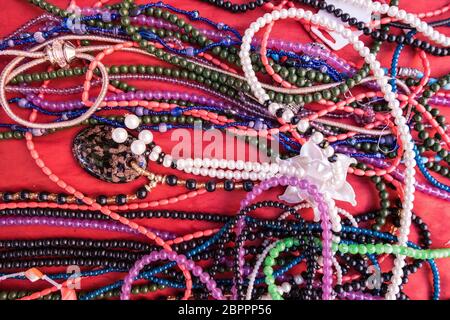 Hintergrund der bunte Armbänder und Halsketten zum Verkauf auf einem Flohmarkt mit rotem Samt Hintergrund. Stockfoto