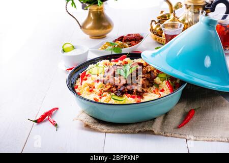 Tajin mit Couscous, Gemüse und Fleisch auf weißem Hintergrund Stockfoto