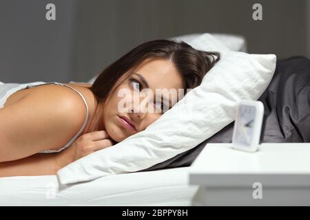 Schlaflose insomniac Mädchen an Wecker liegen auf einem Bett in der Nacht zu Hause suchen Stockfoto