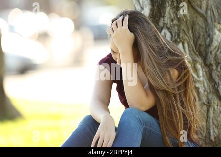 Einzige traurige Frau sitzt in einem Park zu beklagen Stockfoto