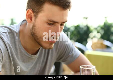 Porträt eines sehr traurig einzigen Mannes allein sitzen und trinken außerhalb in einer Restaurantterrasse Stockfoto