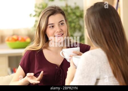 Zwei entspannte Freunde reden und trinken, sitzen auf einem Sofa im Wohnzimmer zu Hause Stockfoto