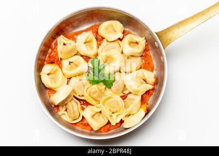 Tortellini auf Weiß mit Tomatensauce. Stockfoto