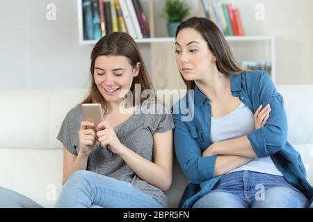 Mädchen Spionage die telefonische Nachrichten von ihrem Freund auf einer Couch im Wohnzimmer zu Hause sitzen Stockfoto