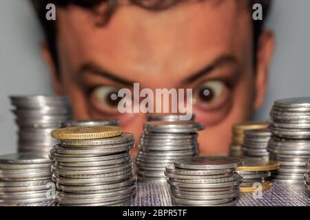 Fokus auf Münze. Ein reichhaltiges gierig älterer Mann schaut auf Münzen. Der Kollektor sieht seinen Reichtum. Ein älterer Mann in Metall Geld starrte auf den Boden. Stockfoto