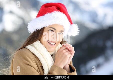 Smiley Frau auf weihnachtsferien Blick auf Sie mit einem schneebedeckten Berg im Hintergrund Stockfoto