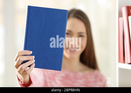 Glückliche Frau zeigt ein leeres Deckblatt eines Buches zu Hause Stockfoto