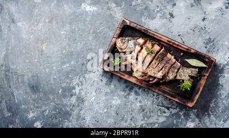 Gegrillter Fisch mit Zitrusfrüchten, Kräutern und Gewürzen auf rustikale Küche geladen Stockfoto