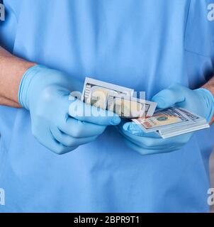 Arzt in der blauen Uniform und Handschuhe erzählt Geld, das Konzept des Gebens für medizinische Dienste Stockfoto