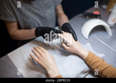 Schönheitssalon, Anwendung feuchtigkeitsspendende Creme auf Client Hände und massieren. Maniküre im Salon. SPA Maniküre, Handmassage und Körperpflege. Nahaufnahme Stockfoto