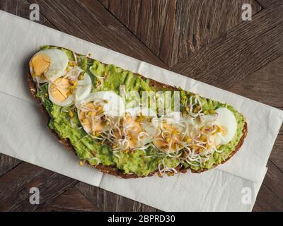 Leckere bio Brot mit Avocado Sahne und Eier auf einem rustikalen Holztisch Stockfoto