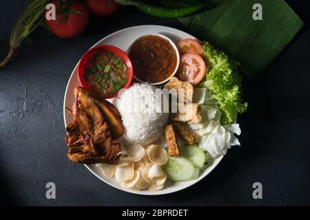 Nasi Lemak kukus mit gebratenen Hähnchen, beliebten traditionellen malaysischen lokalen Essen. Flach nach oben Ansicht von oben. Stockfoto