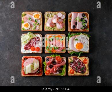 Satz von acht verschiedenen Sandwiches mit Fleisch in quadratische Form. Top View oder flach. Sortiment Fleisch Toast auf schwarzem Hintergrund. Idee, kreative Konzept Stockfoto