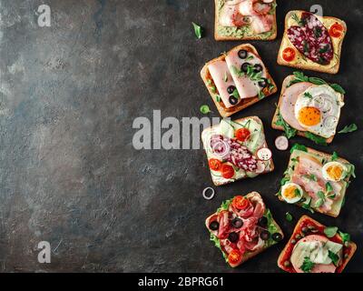Set aus acht verschiedenen Sandwiches mit Fleisch, kopieren Raum für Design oder Text. Draufsicht oder flaches Lay. Fleischtoastgerichte auf schwarzem Hintergrund. Idee, cr Stockfoto