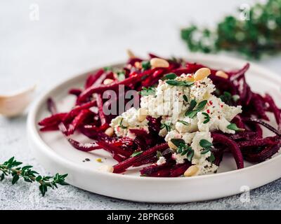 Roher Rote Bete Spaghetti Salat mit Weichkäse, Nüssen, Thymian. Gemüsennudeln - frische Rote Bete Nudeln mit Ricotta und frischem Thymian auf dem Teller. Spa kopieren Stockfoto