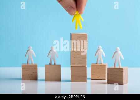 Hand menschliche Figur über Gestapelte Holzklotz auf weißem Schreibtisch Stockfoto