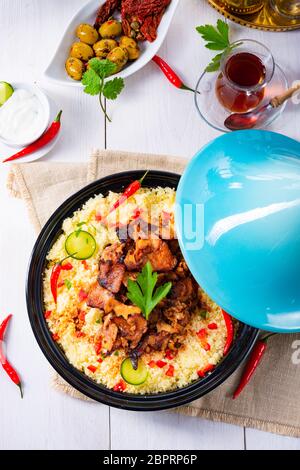 Tajin mit Couscous, Gemüse und Fleisch auf weißem Hintergrund Stockfoto