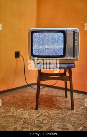 Vintage-Fernseher auf einem Stuhl in einem leeren Raum Stockfoto
