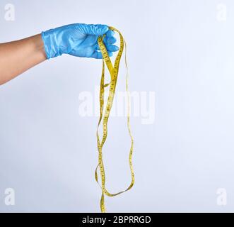 Blau sterile behandschuhte Hand mit einem gelben Maßband auf weißem Hintergrund Stockfoto