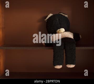 Alter und verlassene Teddybär auf leerem Regal Stockfoto