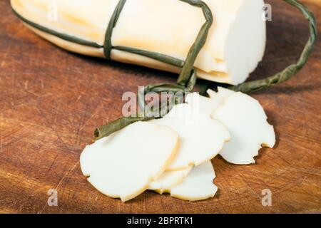 In Scheiben geschnitten lokale italienische Provola Affumicata (geräucherter provola) Käse auf dunklem Holz Schneidebrett aus der Nähe Stockfoto