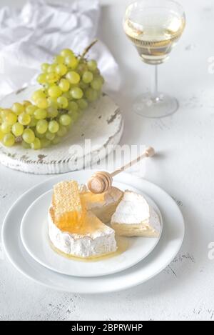 Camembert mit Honig, Trauben und Glas Weißwein Stockfoto