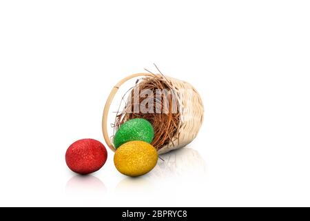 Bunte Ostereier aus Nest auf Holz- korb über weißem Hintergrund verschüttet. Frohe Ostern Stockfoto