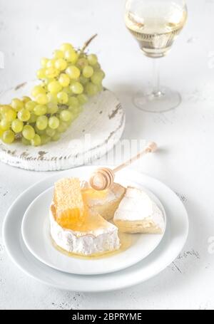 Camembert mit Honig, Trauben und Glas Weißwein Stockfoto