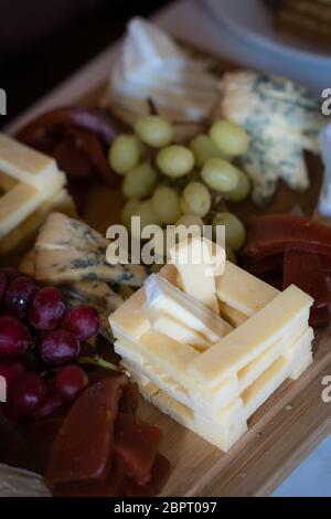 Käseplatte mit verschiedenen Käsesorten einschließlich Brie, Cheddar und Blauschimmelkäse, serviert mit Trauben Stockfoto