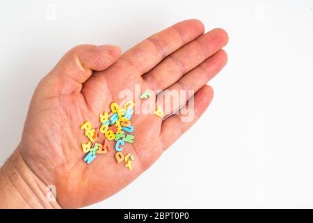 Die bunten Buchstaben, die in der Palme einer Hand verstreut Stockfoto