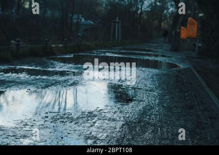 Spiegelung des bewölkten Himmels in Pfützen auf einer sandigen Straße in Berlin. Foto nach einem Regenschauer. Stockfoto