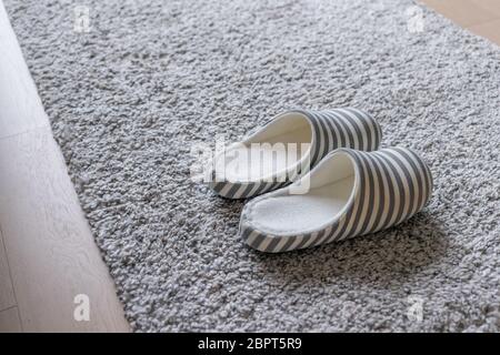 Pantoffel auf grauem Teppich auf dem Boden zu Hause Stockfoto