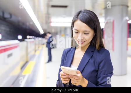 Geschäftsfrau, die am Handy im Bahnhof arbeitet Stockfoto