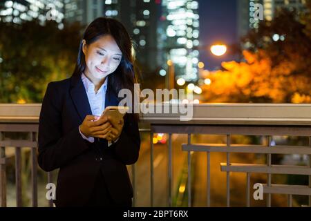 Geschäftsfrau, die nachts in Tokio Handy arbeitet Stockfoto