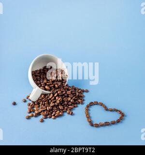 Kreative Valentinstag Konzept Foto Tasse Kaffee mit Liebe urlaub Feier Herz aus Bohnen auf blauem Hintergrund. Stockfoto