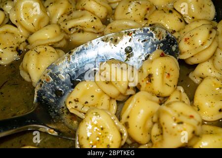 Kleine Knödel werden in einer Pfanne mit Gewürzen gekocht. Nahaufnahme Stockfoto
