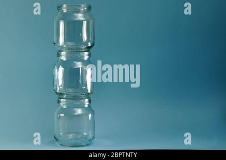 Vertikale Reihe von Glasgefäßen auf der linken Seite auf einem horizontalen blauen Hintergrund. Stockfoto