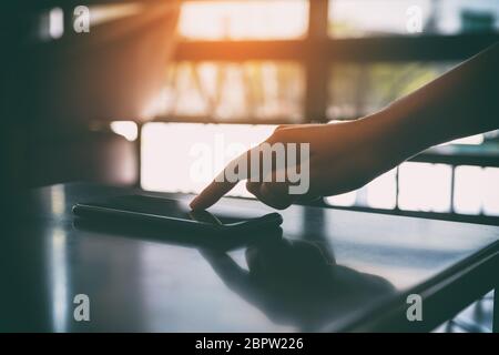 Ein Finger, der auf das Mobiltelefon auf dem Tisch zeigt Stockfoto