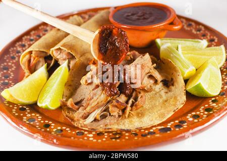 Mexican Carnitas Tacos ist traditionelle Schweinefleisch Taco mit Mais-Tortilla und Sauce in Mexiko-Stadt auf weißem Hintergrund Stockfoto