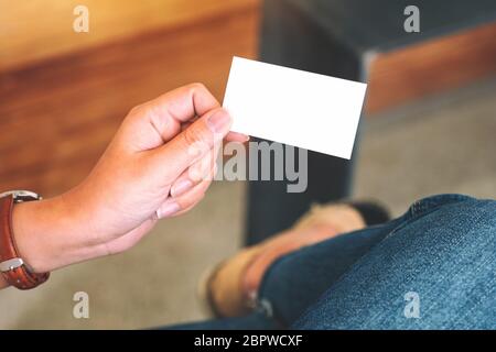 Eine Hand, die weiße leere Visitenkarte mit verschwommenem Hintergrund enthält Stockfoto