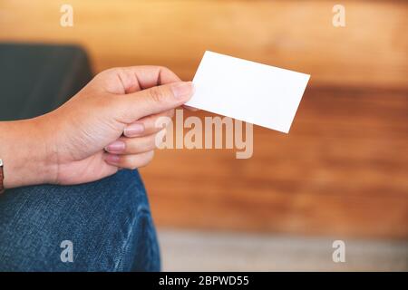 Eine Hand, die weiße leere Visitenkarte mit verschwommenem Hintergrund enthält Stockfoto