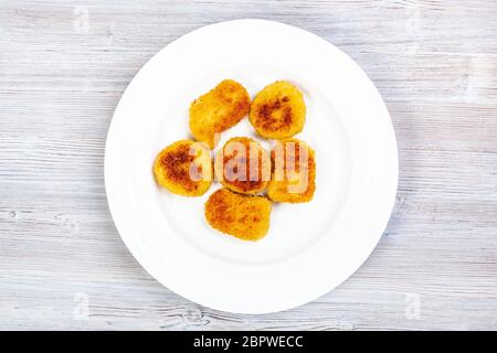 Draufsicht auf die Portion gebratener Hähnchennuggets auf weißem Teller auf grauem Holzbrett Stockfoto