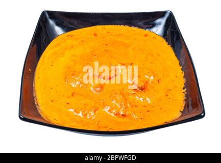 Indische Küche - Portion Chicken Tikka Masala (Stücke von gerösteten marinierten Huhn in würziger Curry cremige Sauce) in schwarzer Schüssel auf weißem Bac isoliert Stockfoto