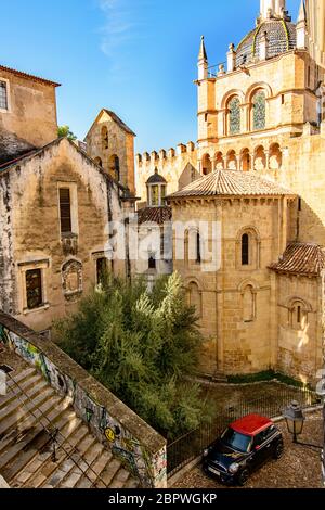 Blick auf die Rückseite der SE Velha Kathedrale in Coimbra, Portugal mit einem Mini Cooper im Vordergrund Stockfoto
